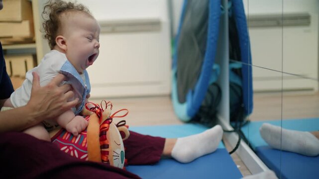 Parent engaging infant with developmental challenges in playful exercises, focusing on physical therapy and early childhood development