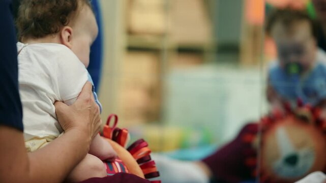 Parent supporting a baby looking at its reflection in a mirror, fostering early childhood exploration and self-discovery in a playroom
