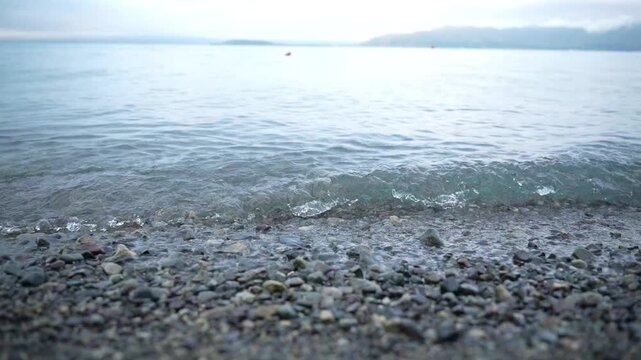 The coastal part of Lake Sevan with its mirror under clear water and beach view of the shore