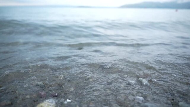 The coastal part of Lake Sevan with its mirror under clear water and beach view of the shore