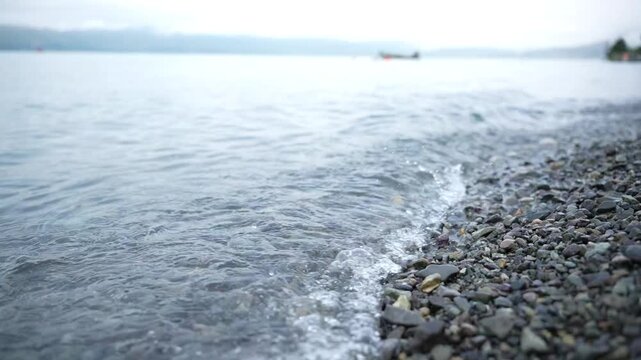 The coastal part of Lake Sevan with its mirror under clear water and beach view of the shore