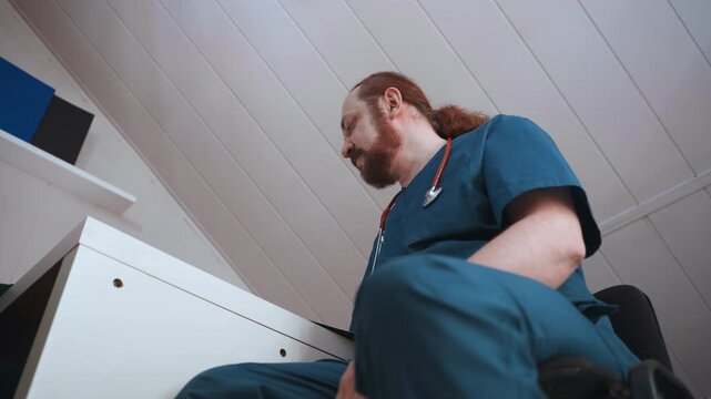 Home visit nurse white male paramedic sitting at desk recording notes in living room, blue scrubs and stethoscope visible, low angle perspective, calm focused expression, athome medical documentation