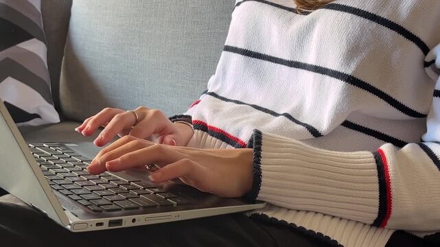 Clos up view of a young freelancer woman working comfortably from her modern living room sofa