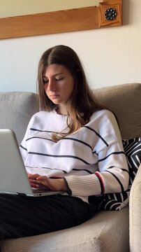 Young woman studying online with a laptop from a sofa at home, changing emotions from happy to bored, showing the complexities of remote e-learning and communication