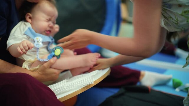 Baby is engaged in a sensorimotor exercise, working on development with guidance from a therapist and mother supporting