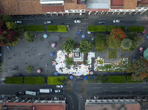 Aerial view of the main plaza in Centro with a central monument, lush green trees, pedestrian walkways, and surrounding streets with traffic in Uruapan, Michoacan, Mexico.