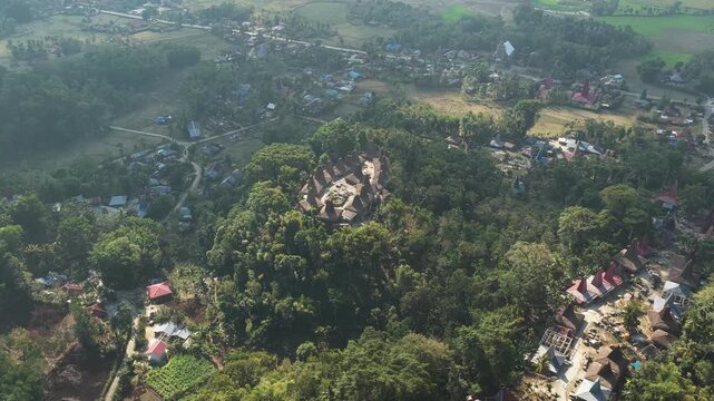 Aerial view of Kampung Prai Ijing traditional village with thatched-roof houses nestled in lush green hills in Kota Walkabubak, East Nusa Tenggara, Indonesia.