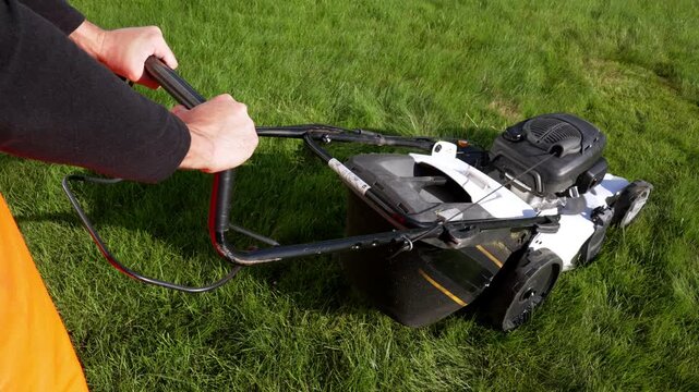 Person pushes lawn mower across green grass. Grass appears lush and evenly cut. Mower moves steadily with deliberate motion. Ideal for garden maintenance or outdoor activity scenes