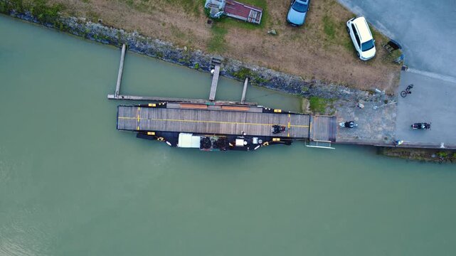 Top down aerial view of motorcyclists riding off a small cable ferry as it docks on the bank of the river Danube near Haibach ob der Donau, Upper Austria, on a summer day. Shot on August 7, 2026.