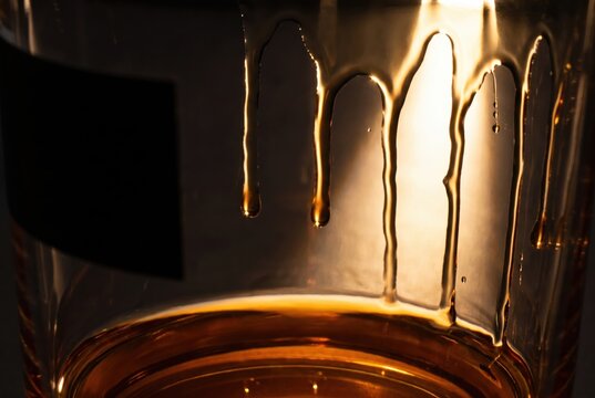 Warm honey jar dripping in backlit glass with golden amber glow