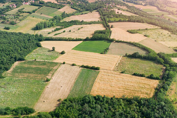 Fototapeta premium Warm golden summer light bathes a patchwork of rolling farmland and a small village nestled among wooded hills. Rural Europe concept.