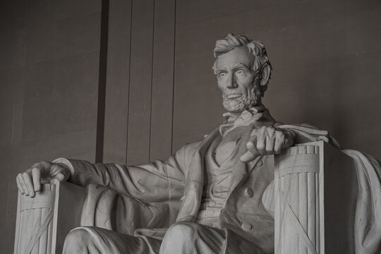 View of the marble statue of Abraham Lincoln seated in the Lincoln Memorial, captured with soft interior lighting and detailed stone textures in Washington, District of Columbia, United States.