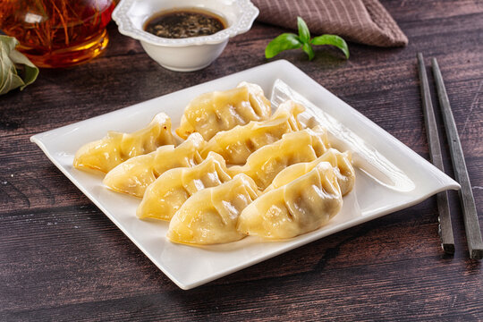 Gedza dumplings on white plate with dipping sauce and chopsticks