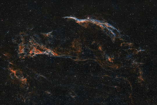 View of the Western Veil Nebula, also known as the Witch's Broom Nebula, showing intricate filaments of ionized gas and glowing dust clouds against a dense star field in deep space, Poland.
