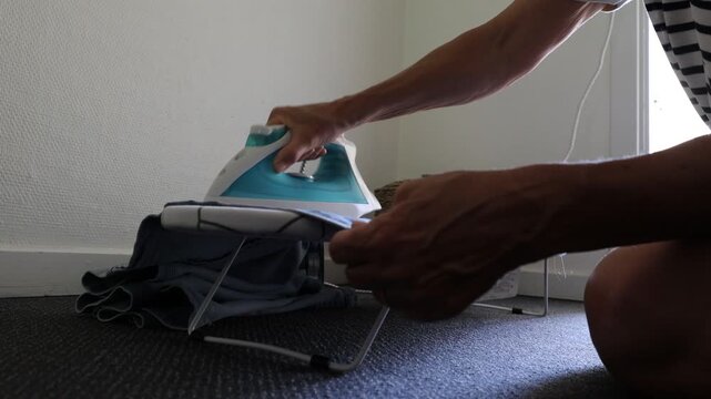 Gram, Denmark A woman irons a shirt on a miniature ironing board in a hotel room. 