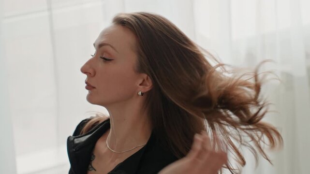 Woman relaxes after workout. Calm woman cares for hair. Serene woman tending to hair after exercise session. Peaceful woman engaging in selfcare routine following physical activity at her residence