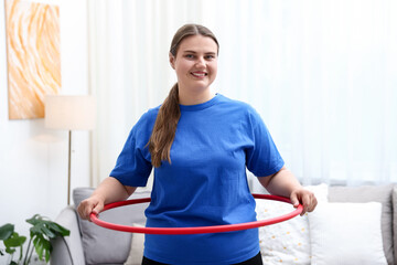 Overweight woman exercising with hula hoop at home © New Africa