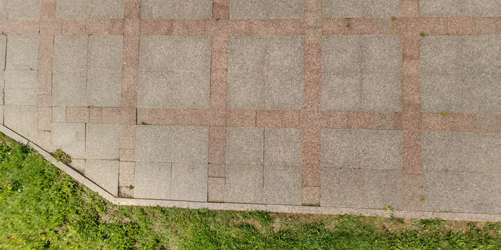 top view of the texture of paving slabs on pedestrian path with grass