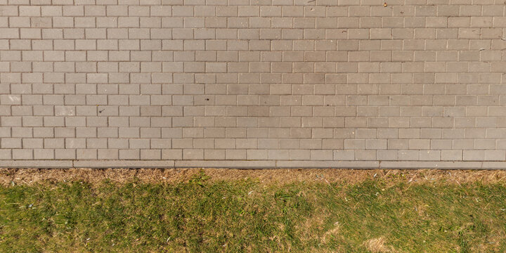 top view of the texture of paving slabs on pedestrian path with grass