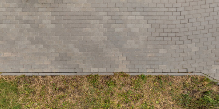top view of the texture of paving slabs on pedestrian path with grass