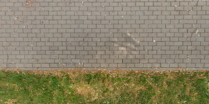 top view of the texture of paving slabs on pedestrian path with grass