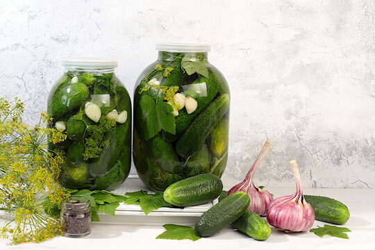 Pickled cucumbers in a jar with garlic and dill on the kitchen table, village harvest, homemade pickling recipe, cucumbers and ingredients for pickling, home canning concept, healthy and natural food