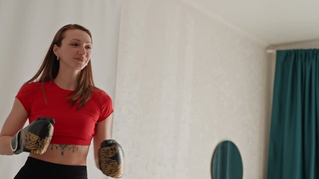 Caucasian woman shadowboxing inside house, precision jab and hook drills with gloves, steady stance and core engagement, mirror and curtain in background, concentrated expression, training intensity