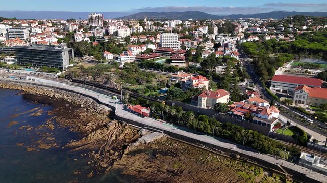 Aerial view of Avenida Marginal coastal road with buildings and rocky coastline in Estoril, Lisboa, Portugal.