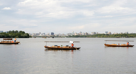 Wooden rowing boats on West Lake, with Hangzhou skyline, China © C