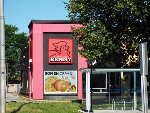 Gatineau, Quebec, Canada &ndash; June 24, 2026: A "R&ocirc;tisseries Benny restaurant" building with a distinctive red and black exterior features a sign showing a stylized rooster logo and food advertisement at 
