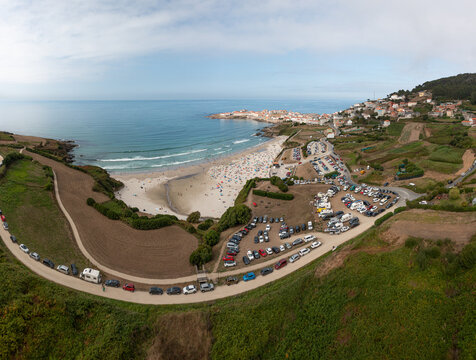 Aerial view of the sandy beach and parking areas filled with cars in the coastal town of Caion, A Coruna, Spain.