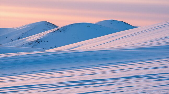 Snowy hills landscape under soft pink sunset sky. White winter terrain with blue shadows across rolling mounds. Scenic mountain view creates calm atmosphere. Frozen nature environment provides