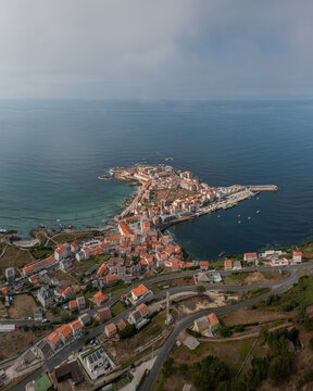 Aerial view of the coastal town of Caion featuring a harbor, traditional houses, and rocky coastline in Caion, A Coruna, Spain.