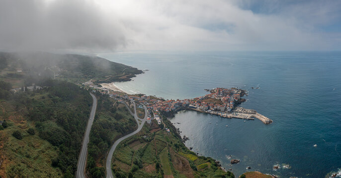 Aerial view of the coastal town of Caion with its harbor, sandy beach, and winding road along the Atlantic coastline in Caion, A Coruna, Spain.