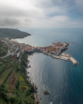 Aerial view of the coastal town of Caion with its harbor, stone buildings, and surrounding cliffs along the Atlantic Ocean in Caion, A Coruna, Spain.