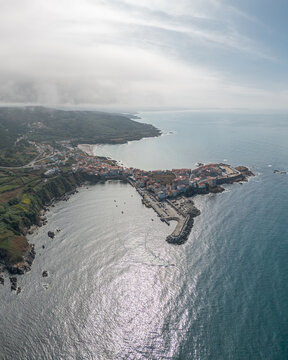 Aerial view of the coastal town of Caion with its harbor, breakwater, and historic buildings nestled along the rocky coastline of the Atlantic Ocean in Caion, A Coruna, Spain.