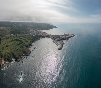 Aerial view of the coastal town featuring a harbor, rocky cliffs, and Atlantic waters in Caion, A Coruna, Spain.