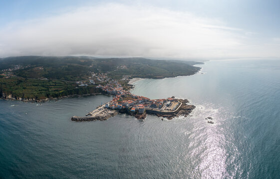 Aerial view of the coastal town of Caion, featuring its harbor, historic buildings, and rocky coastline along the Atlantic Ocean in Caion, A Coruna, Spain.