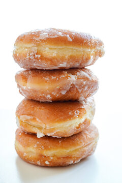 Freshly baked glazed donuts stacked vertically on white background