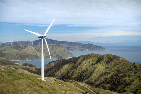 View of the wind farm at Ohariu Valley with large wind turbines on rolling green hills overlooking the ocean in Wellington, Wellington Region, New Zealand.