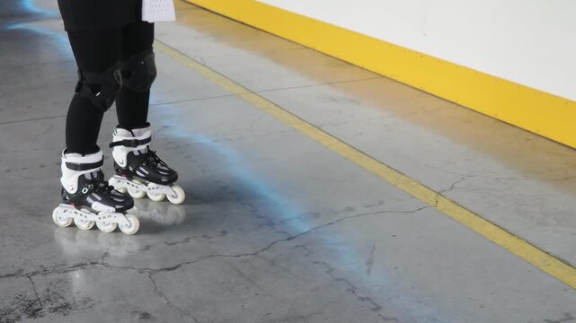 Girl roller skating having fun indoors. A girl learns to roller skate on a special area wearing a helmet and knee pads. Active sports for children
