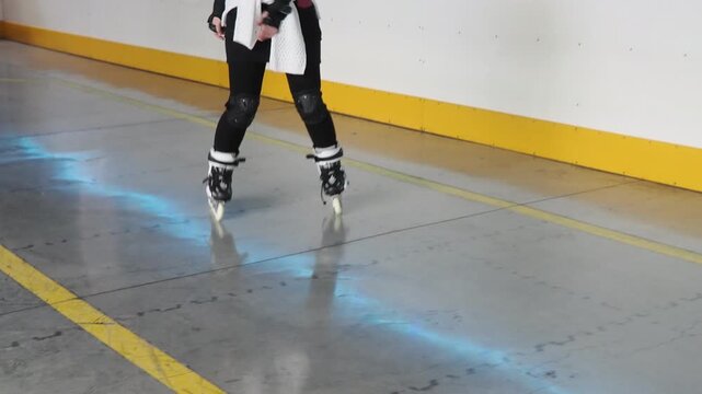 Girl roller skating having fun indoors. A girl learns to roller skate on a special area wearing a helmet and knee pads. Active sports for children
