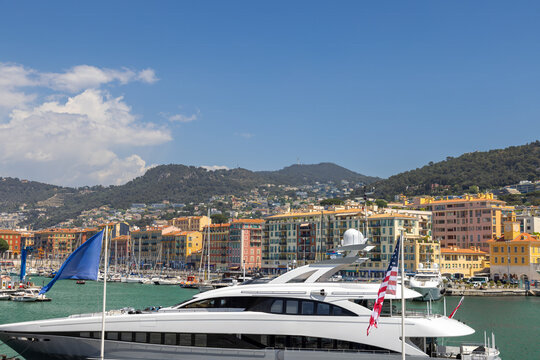 View of luxury yachts and boats docked at the Nice Port and Marina, with colorful Mediterranean buildings and hills in the background, Nice, Provence-Alpes-Cote d'Azur, France.