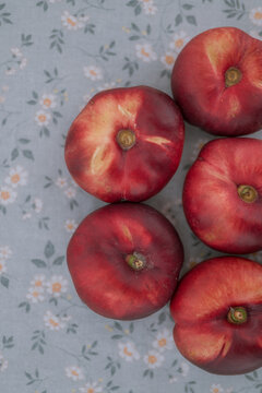 Ripe flat nectarines viewed from above on floral fabric