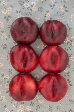 Stacked red nectarines on pale blue floral fabric