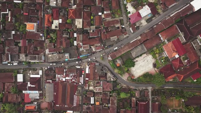 Aerial view of dense residential area with traditional terracotta rooftops and narrow streets in Kecamatan Sidemen, Bali, Indonesia.