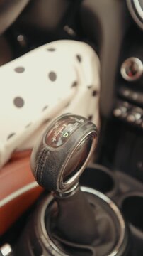 Close-up of an automatic transmission gear shifter in Drive mode inside a moving car, showing the driver's hand and interior. Vertical video