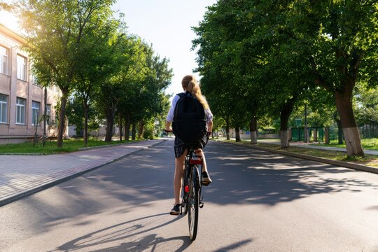 Happy Child Cycling to School with Backpack on Back