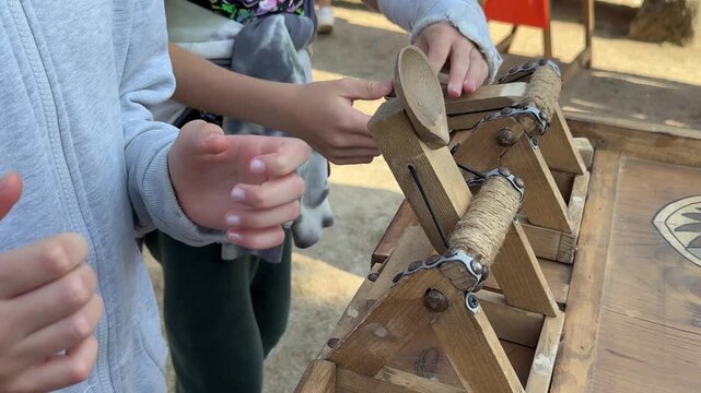 Children using wooden mechanical game device, hands close up at outdoor fair