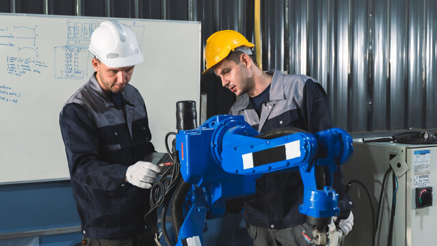 Engineering Professionals inspecting robotic components Around an Industrial Robot During Maintenance and Quality Inspection